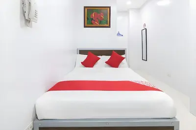 a bedroom with a white bed with red pillows at OYO 152 Sangco Condotel in Manila