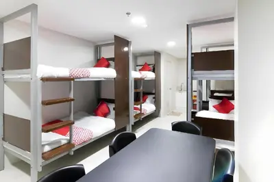 a room with bunk beds and a table and chairs at OYO 152 Sangco Condotel in Manila