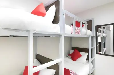 a bunk bed room with white bunk beds with red pillows at OYO 152 Sangco Condotel in Manila