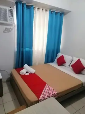 a bedroom with a bed with blue curtains at Urban Deca Tower OYO 3 in Manila
