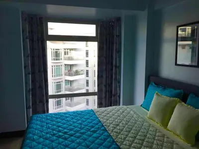 a bedroom with a bed and a large window at Ameer Condotel @ Parkside Villa in Manila