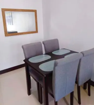 a dining room table with chairs and a mirror at Ameer Condotel @ Parkside Villa in Manila