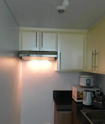a kitchen with white cabinets and a stove top oven at Ameer Condotel @ Parkside Villa in Manila