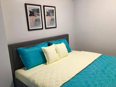 a bed with blue and white pillows in a bedroom at Ameer Condotel @ Parkside Villa in Manila