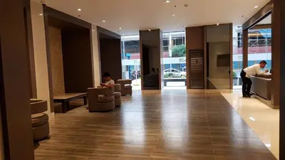 a lobby with two people sitting in chairs in a building at 1 Bedroom Apartment @SMDC Shore Residences, Mall of Asia in Manila