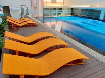 a swimming pool with orange chairs in front of a building at 101 Newport City Chillax C2 Manila Airport Pasay in Manila