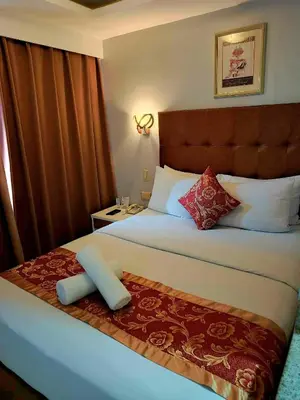 a bedroom with a large bed with a large headboard at JMM Grand Suites in Manila