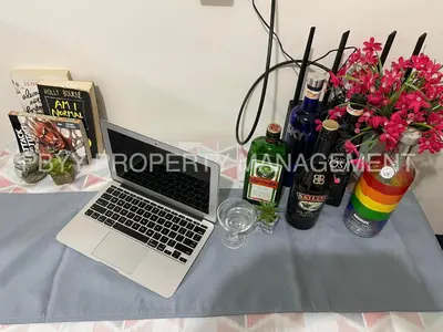 a laptop computer on a table with bottles and flowers at Shore Residences, Mall Of Asia Complex Stays by PBYY in Manila