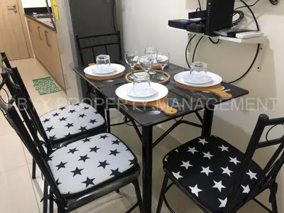 a black table with two chairs and glasses on it at Shore Residences, Mall Of Asia Complex Stays by PBYY in Manila