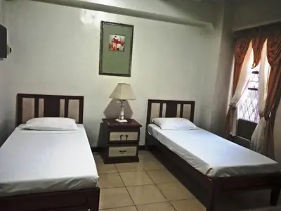a room with two beds and a table with a lamp at Casa Micarosa Hotel in Manila
