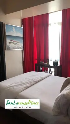 a bedroom with a bed with red curtains and a window at SAN LORENZO PLACE 2BR 29-E by LARICO in Manila