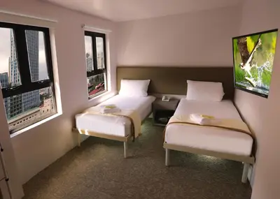 two beds in a room with two windows at 1010 Hotel in Manila