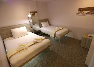 a hotel room with two beds and a chair at 1010 Hotel in Manila