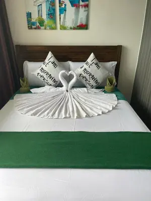 a white bed with pillows with a heart made up at Green Residences Stays by PBYY in Manila