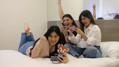 three girls laying on a bed with their cell phones at Red Planet BGC The Fort in Manila