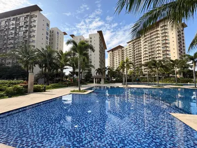a large swimming pool with palm trees and buildings at Cozy Staycation at Eastbay Residences in Manila