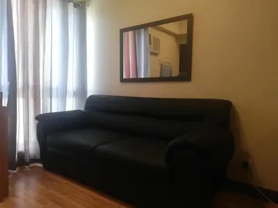 a black couch in a living room with a mirror at Cozy Staycation at Eastbay Residences in Manila