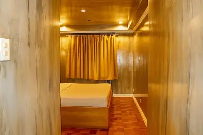 a small bedroom with a bed and a yellow curtain at CONNECTOR Hostel in Manila