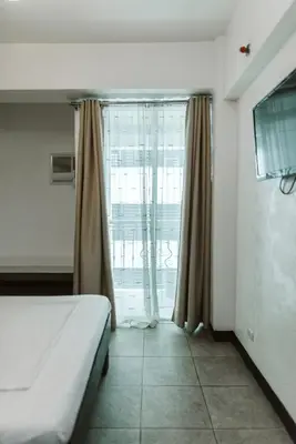 a bedroom with a bed and a large window at San Agustin Residences in Manila