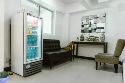 a room with a refrigerator and a chair and a table at San Agustin Residences in Manila