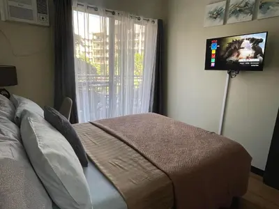 a bedroom with a bed and a flat screen tv at MaRoy Suites at Asteria Residences (Near NAIA with free Parking+Fiber Internet) in Manila