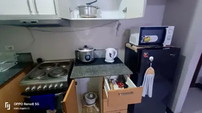 a small kitchen with a stove and a refrigerator at Cubao ManhattanHeights Unit 7EF Tower B, 1BR in Manila