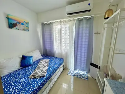 a bedroom with a bed with blue sheets and a window at Santiorini at Shore Residences in Manila