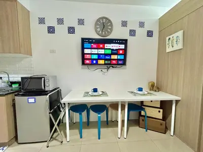 a kitchen with a table and a tv on the wall at Santiorini at Shore Residences in Manila