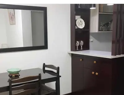 a dining room with a table and a clock on a wall at Estien’s Cozy Condotel to Stay in Imus