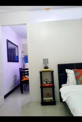 a bedroom with a bed and a table with a lamp at Estien’s Cozy Condotel to Stay in Imus