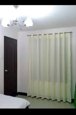 a bedroom with a white curtain and a bed at Estien’s Cozy Condotel to Stay in Imus