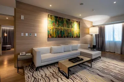 a living room with a white couch and a painting at Brittany Hotel BGC in Manila