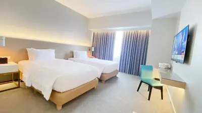 a hotel room with two beds and a desk and a chair at Brittany Hotel BGC in Manila
