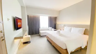 a hotel room with a large white bed and a chair at Brittany Hotel BGC in Manila