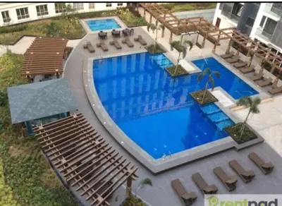 an overhead view of a large swimming pool with lounge chairs and sidx sidx at Studio Room Walking Airport, In City Of Newport City in Manila