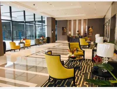 a lobby with yellow chairs and tables in a building at Studio Room Walking Airport, In City Of Newport City in Manila