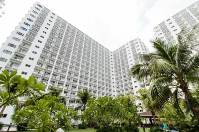 a large building with palm trees in front of it at Luxury condo At Shore 1 Tower C1, Mall of Asia Complex Pasay City in Manila