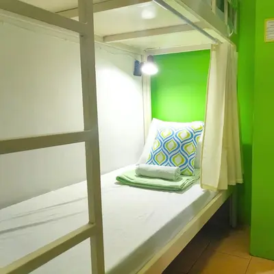 a bunk bed in a green room with a laptop on it at Crossroads Hostel Manila in Manila