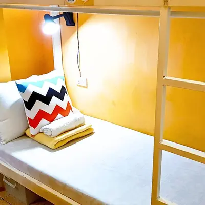 a bunk bed with a pillow and a ladder at Crossroads Hostel Manila in Manila