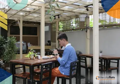 a man sitting at a table in an outdoor restaurant at The City Flats Amorsolo in Manila