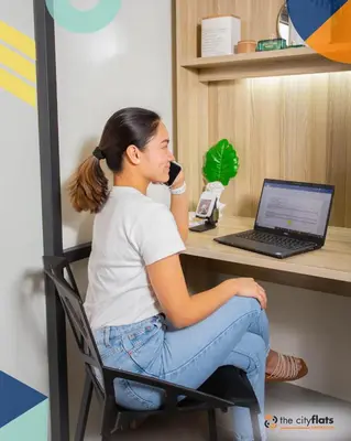 a woman sitting at a desk talking on a phone at The City Flats Amorsolo in Manila