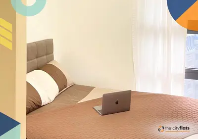 a bedroom with a bed with a laptop on it at The City Flats Amorsolo in Manila