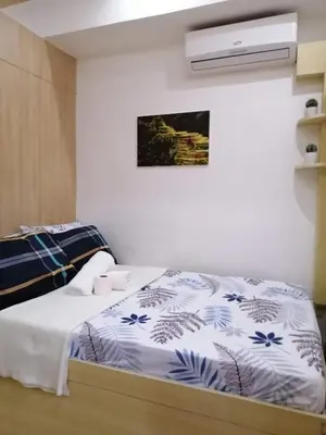 a bedroom with a bed with a blue and white comforter at SMDC GRACE RESIDENCIES in Manila