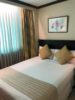 a bedroom with a large white bed with a window at Tower Inn Makati Business Hotel in Manila