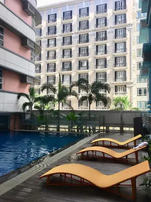 a hotel with a swimming pool in front of a building at Condo 101 Newport in Manila