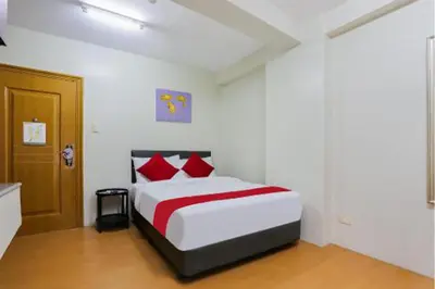 a white bedroom with a bed with red pillows at Anglo Residences Manila in Manila