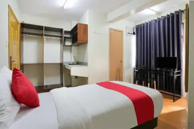 a bedroom with a red and white bed and a kitchen at Anglo Residences Manila in Manila