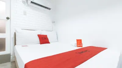 a white bed with two red pillows on it at RedDoorz Plus at BGC near St Lukes in Manila