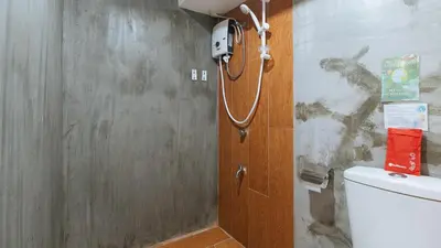 a bathroom with a toilet with a phone on the wall at RedDoorz Plus at BGC near St Lukes in Manila