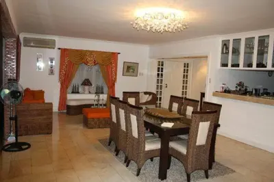 a dining room with a table and chairs and a living room at Casa Meyer's BF Homes International House for rent with pool and Jacuzzi in Manila
